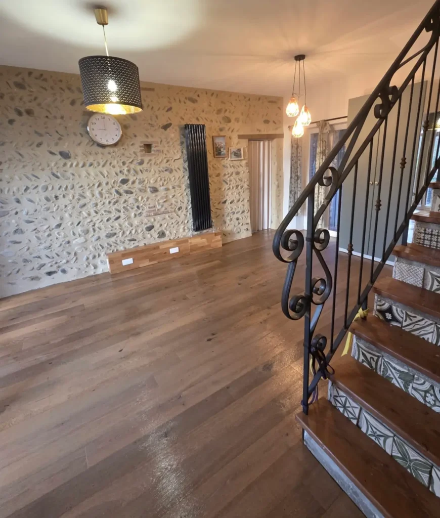 Séjour avec mur en pierre, escalier bois et déco moderne rénové par nl-renovation à Toulouse